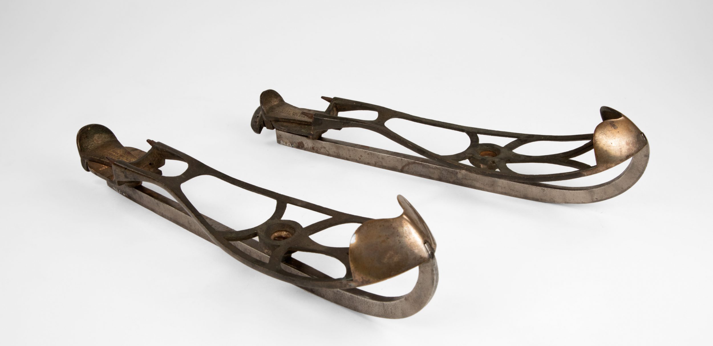 Pair of all metal skate blades, showing the cap at the toe and the clamp-type feature at the heel.