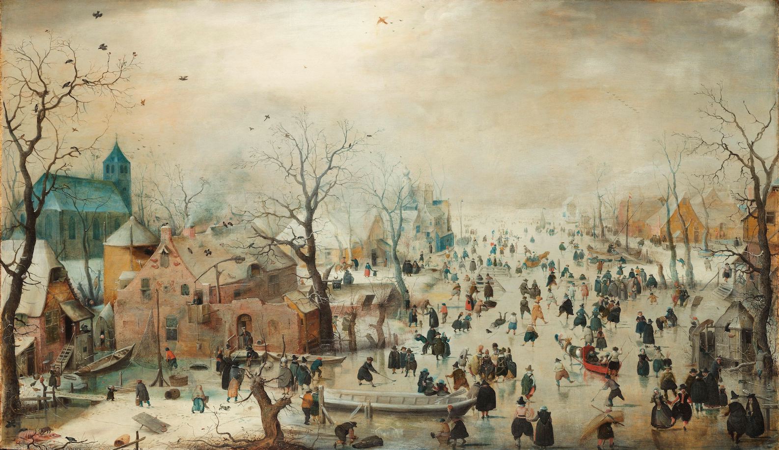 A distant view from above of a large frozen ice surface and buildings to the right and also to the left. People are skating on the ice.