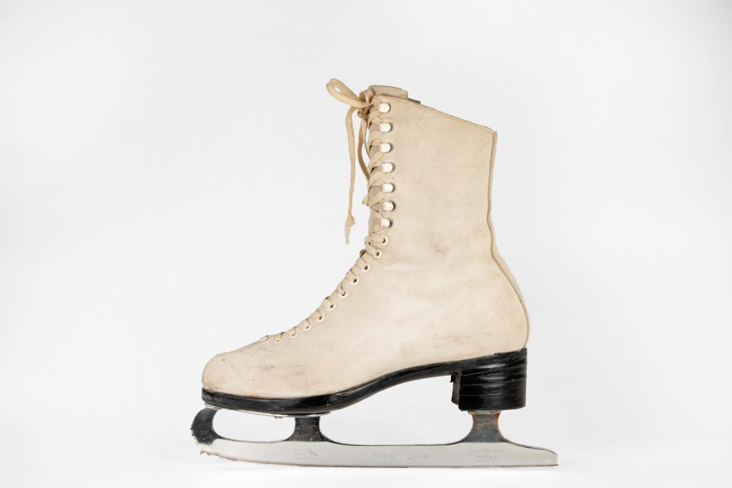 A colour photo of a single off-white woman’s skate in profile view. The stacked leather heel and sole is black.