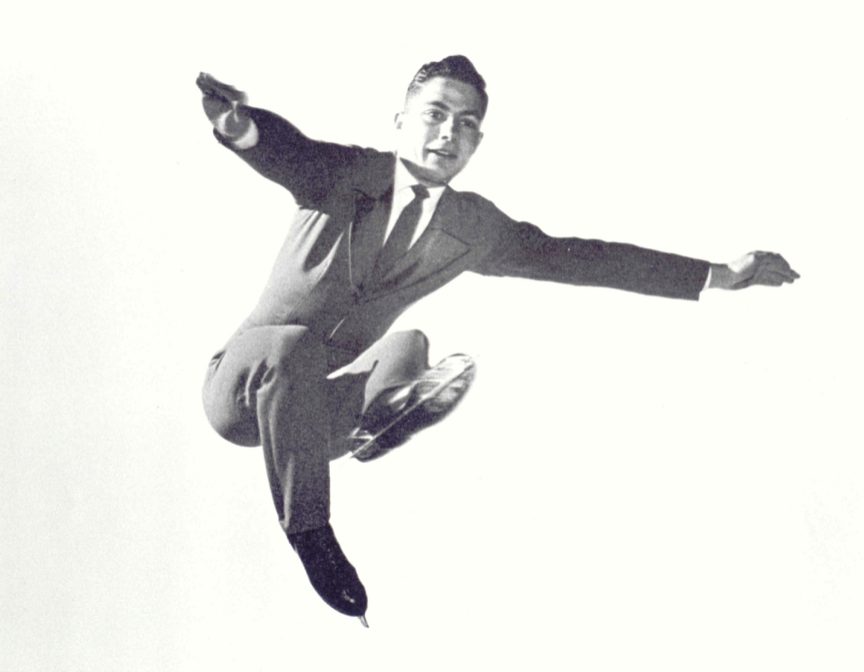 Photo en noir et blanc d’un homme en costume qui saute dans les airs, les genoux repliés et les bras tendus vers l’extérieur. La photo a été prise d’en dessous.