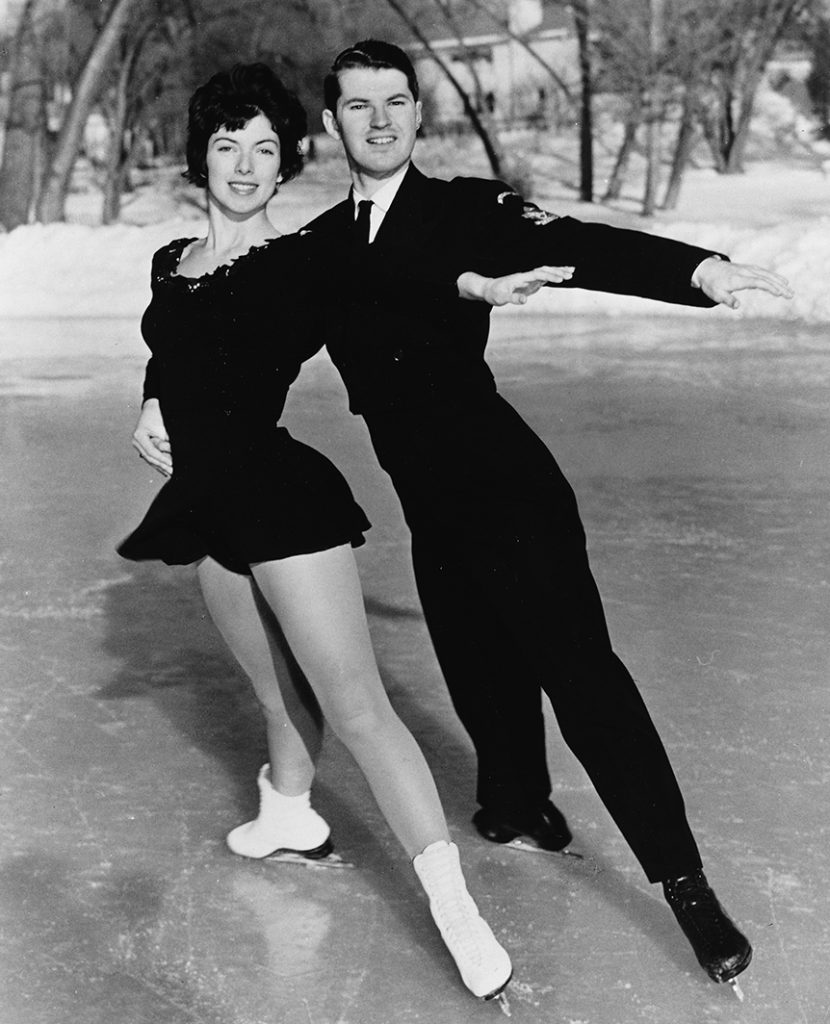 A black and white photo of Virginia Thompson and Bill McLaughlin posing on frozen pond with their left legs extended towards the viewer, the right legs in the opposite direction.