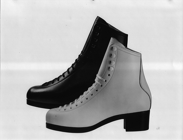 Publicity shot of a black and a white figure skating boot on a white background.