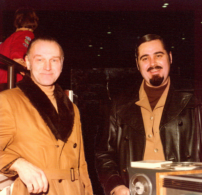 The two men wear winter coats. Langevin sports a goatee and mustache. Dowding’s hair is slicked straight back.
