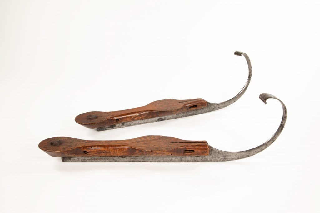 Paire de lames de patins, avec des boucles très exagérées au-dessus de l’orteil, se recourbant du bout avant du patin vers le haut.