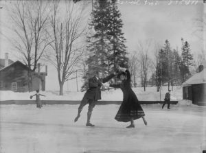 A black and white image of a man and a woman holding hands and performing a skating move on a frozen canal.