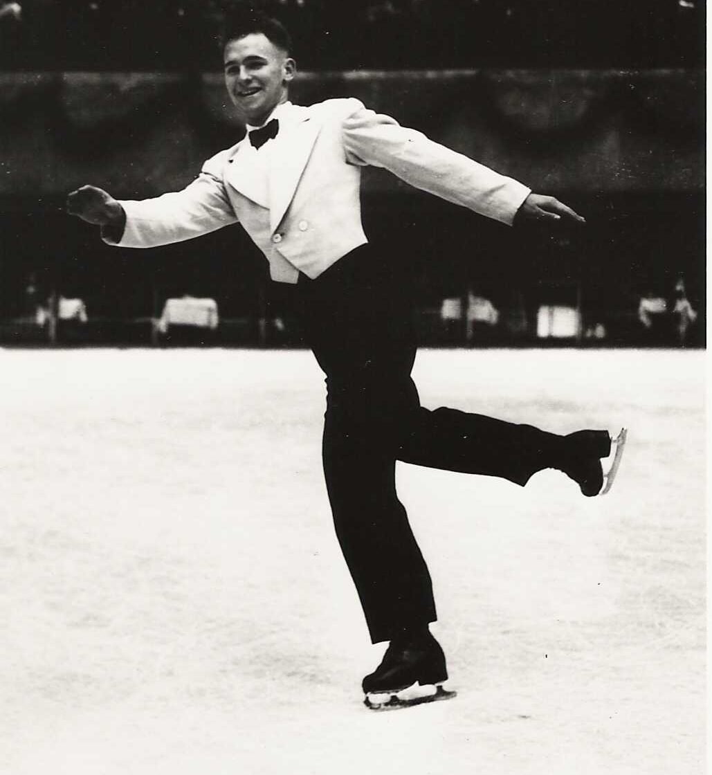 Une photo en noir et blanc de Dick Button portant un pantalon noir, une veste blanche courte et un nœud papillon noir.