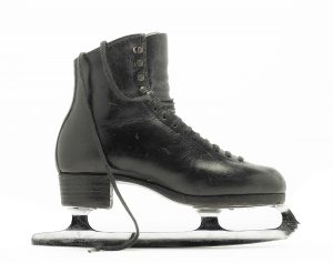 A photo of a black leather skate in profile with laces draping over the boot.